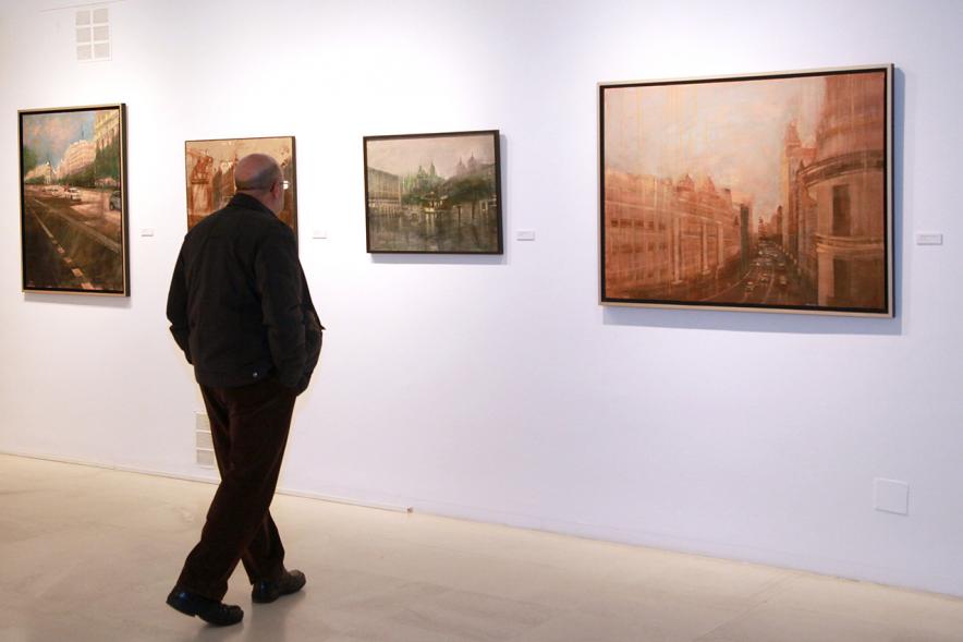 Inauguración Exposición de Charo Vaquerizo "Visiones Urbanas" - Imagen de persona mirando los cuadros de la exposición.