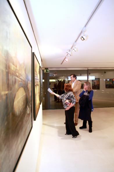 Inauguración Exposición de Charo Vaquerizo "Visiones Urbanas" - Imagen de personas mirando los cuadros de la exposición.
