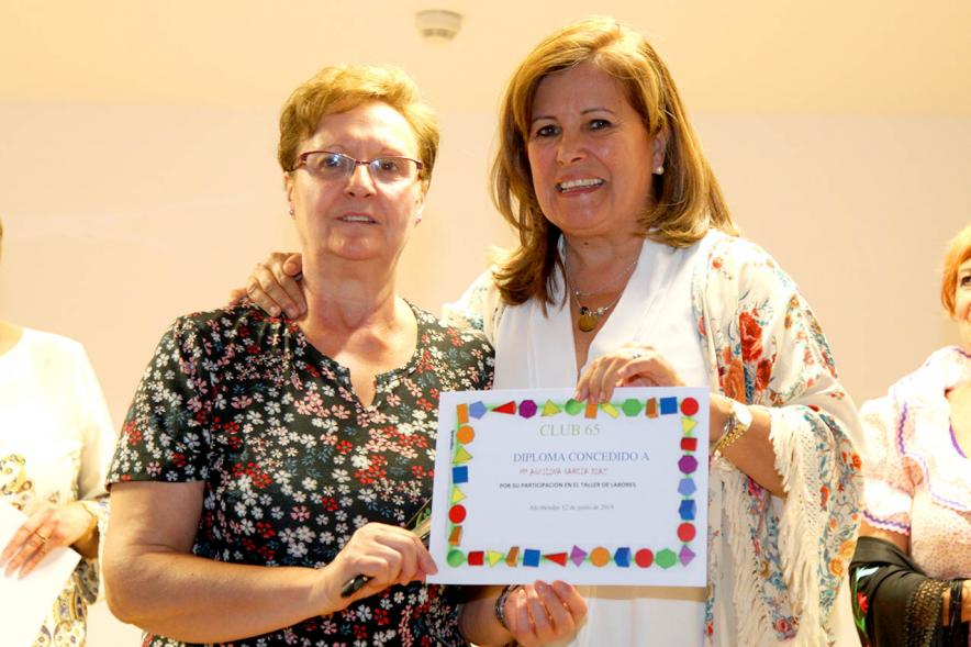Representante del consistorio haciendo entrega del diploma a una galardonada.