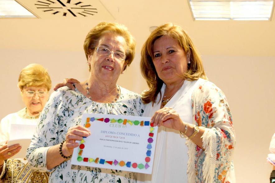 Representante del consistorio haciendo entrega del diploma a una galardonada.