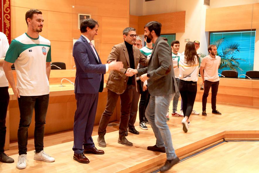 Recepción del Equipo de Natación -  Primer plano del saludo del alcalde Sanchez Acera y las personalidades federativas al entrenador,  rodeados por el equipo.