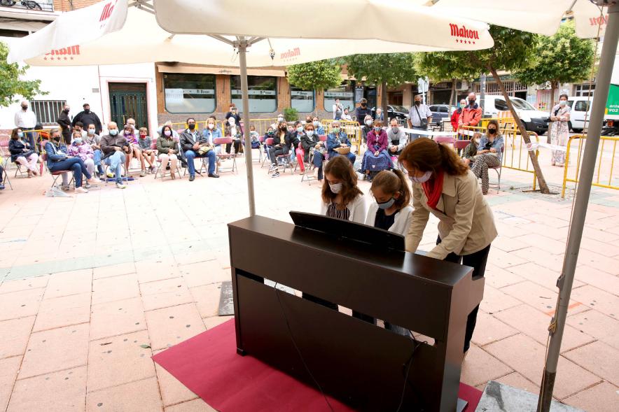 Concierto Infantil Escuela de Música en Distrito Centro - Primer plano de los niños tocando el piano debajo de la  sombrilla.