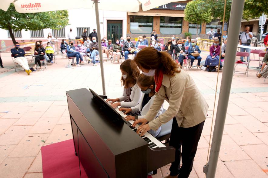Concierto Infantil Escuela de Música en Distrito Centro - Primer plano de los niños tocando el piano  con su profesora.