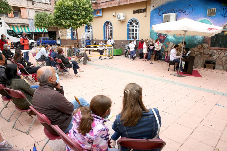 Concierto Infantil Escuela de Música en Distrito Centro - Imagen lateral de los asistentes en círculo y los niños tocando al fondo.