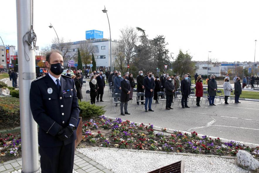 Asistentes en pie mostrando respeto a la bandera con mastil en primer plano
