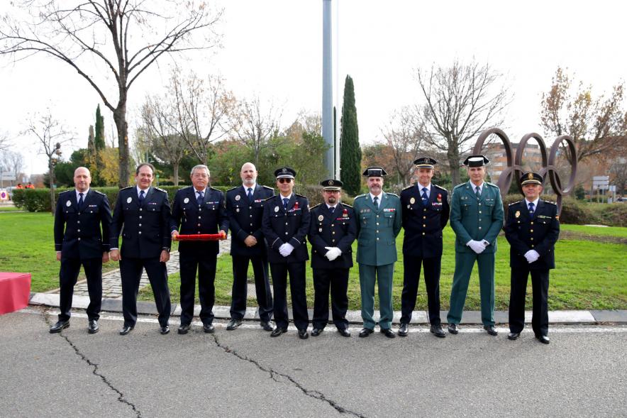 Representantes de los cuerpos y fuerzas de seguridad del estado posando con mástil de bandera al fondo