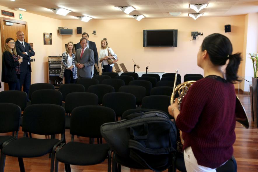 Asistentes al fondo y niña con instrumento 