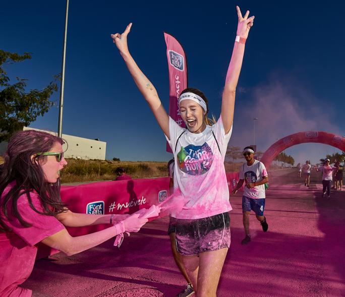 Carrera Color Run - Imagen participante en la carrera con nubes de polvo de color rosa.