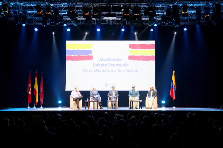 Alcobendas Debate Venezuela - Imagen del escenario con los participantes y el cartel anunciador.