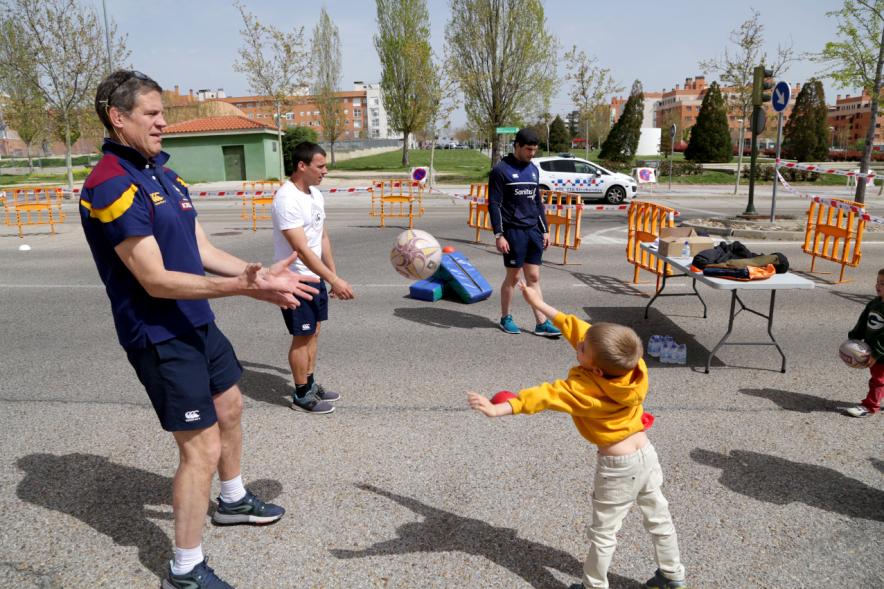 Niño lanzando un balón de rugby, a un jugador de Rugby Alcobendas
