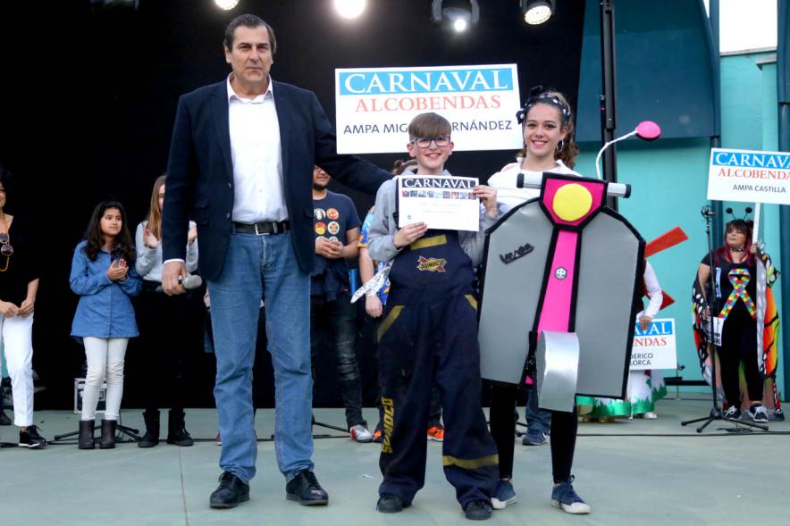 Desfile de Carnaval 2019 - Imagen del concejal de cultura, Fernando Martínez entregando uno de los premios al AMPA CEIP MIGUEL HERNANDEZ de chicas montadas en una vespa y los chicos de mecánicos.