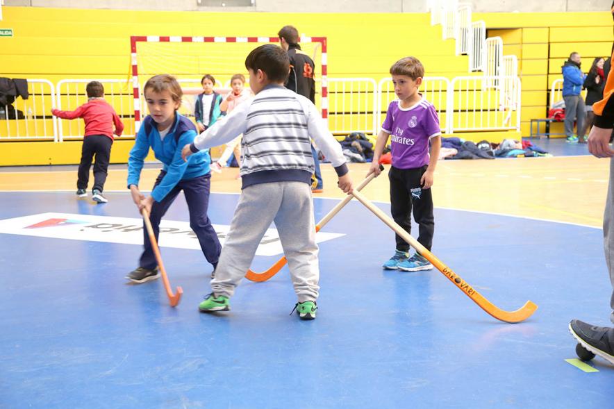 Día Multideportivo por la Integración y la Conciliación -  Imagen  de los niños  preaprandose para jugar al hockey con un monitor.