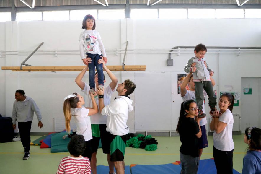 Día Multideportivo por la Integración y la Conciliación -  Imagen de los niños  haciendo ejercicios de gimnasia con los monitores. 