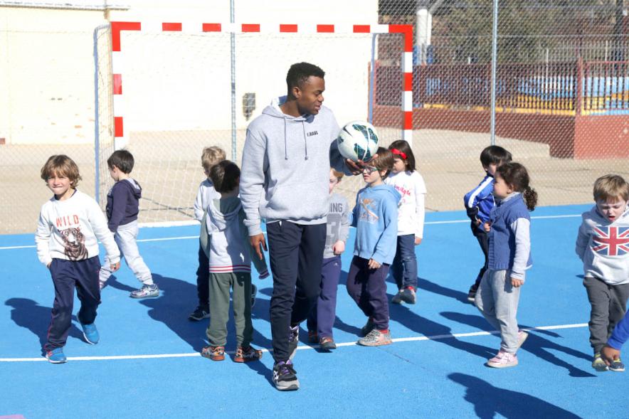 Día Multideportivo por la Integración y la Conciliación - Primer plano de un monitor  con el balón rodeado de niños.