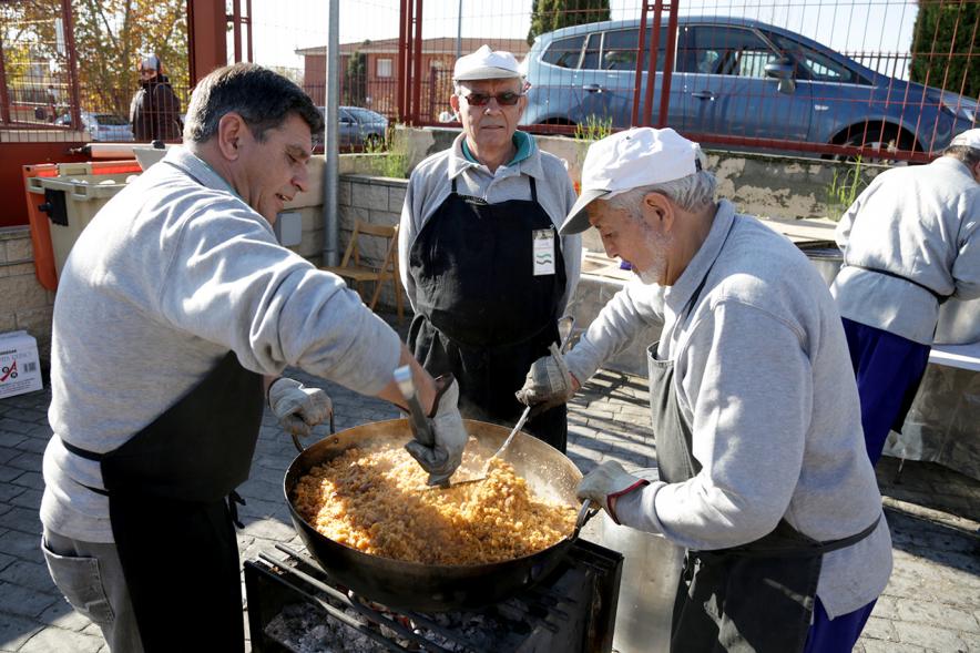 Paellada popular con detalle de hombre sirviendo un plato