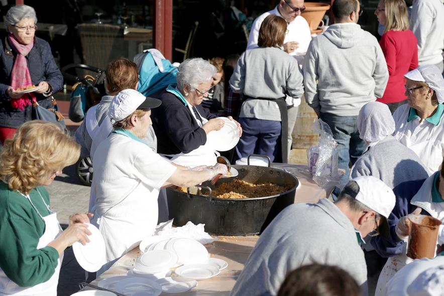 Paellada popular con detalle de mujer sirviendo un plato