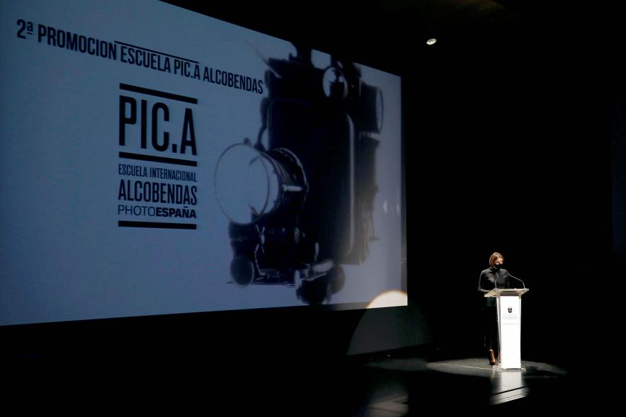 Entrega Diplomas PIC.A Curso 2019-20 - Imagen en penumbra del escenario , el cartel del evento en la pantalla.