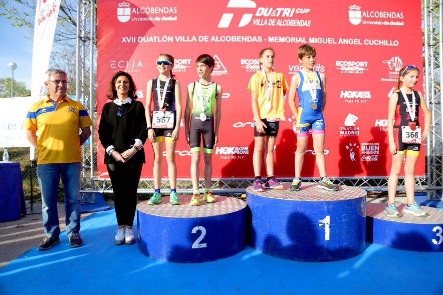 Duatlón Escolar Villa de Alcobendas - Pódium de varias categorías  la concejal de deportes Mar Rodríguez, al lado.