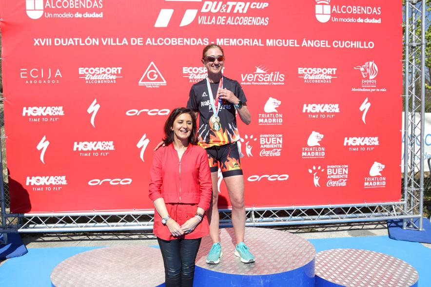 Entrega Premios Campeonato Comunidad de Madrid de Duatlón - Imagen de la concejala de deportes Mar Rodríguez haciendo entrega de un doble premio a un participante.