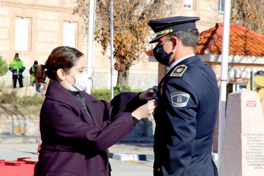 Presentación del ESICAM179 y Entrega de Medallas al Mérito Policial -Imagen de la Presidenta de la Comunidad de Madrid condecorando a un Policía, todos con mascarillas.
