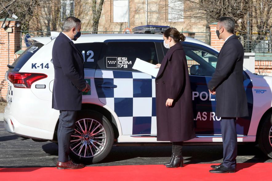 Presentación del ESICAM179 y Entrega de Medallas al Mérito Policial -  Imagen de la Presidenta de la comunidad de Madrid Diaz Ayuso junto a dos colaboradores, colocando unas pegatinas  a  un vehículo policial.