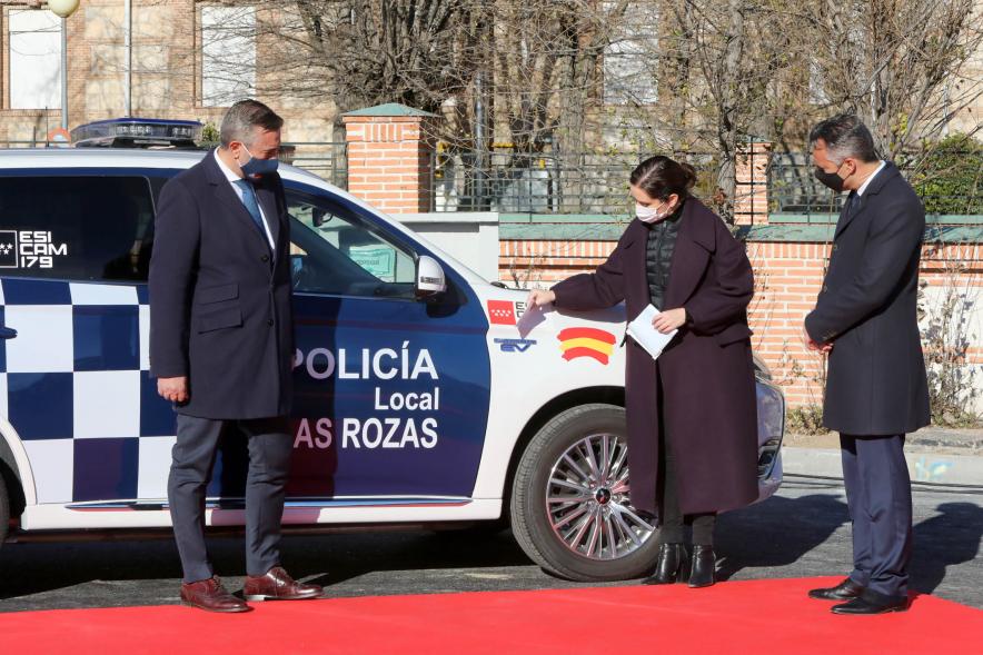 Presentación del ESICAM179 y Entrega de Medallas al Mérito Policial -   Imagen de la Presidenta de la comunidad de Madrid Diaz Ayuso junto a dos colaboradores, colocando unas pegatinas  a  un vehículo policial.