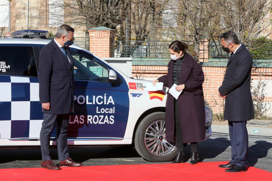 Presentación del ESICAM179 y Entrega de Medallas al Mérito Policial -  Imagen de la Presidenta de la comunidad de Madrid Diaz Ayuso junto a dos colaboradores, colocando unas pegatinas  a  un vehículo policial.