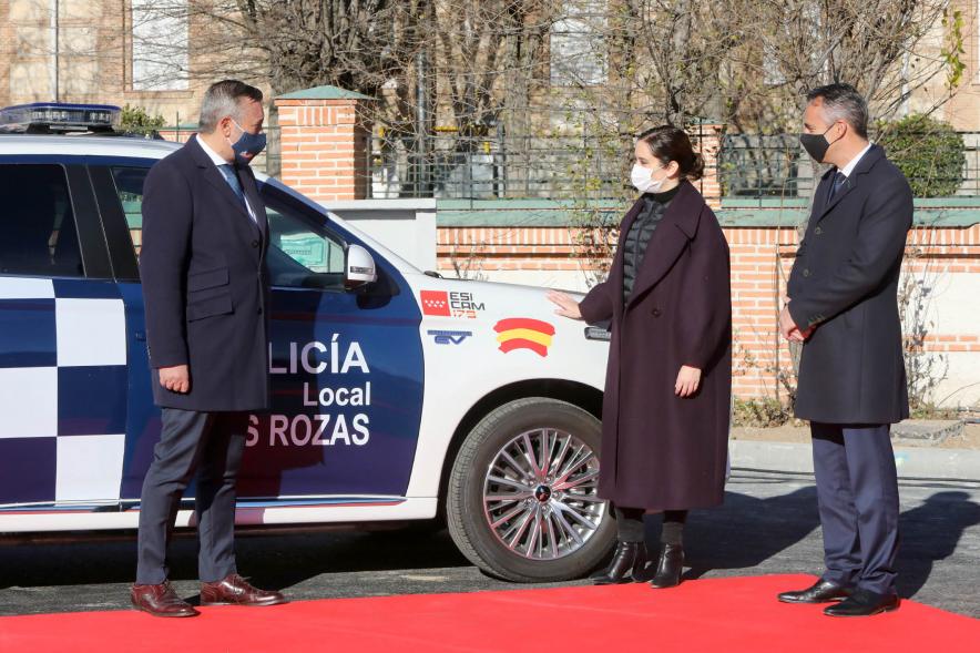 Presentación del ESICAM179 y Entrega de Medallas al Mérito Policial -  Imagen de la Presidenta de la comunidad de Madrid Diaz Ayuso junto a dos colaboradores, colocando unas pegatinas  a  un vehículo policial.