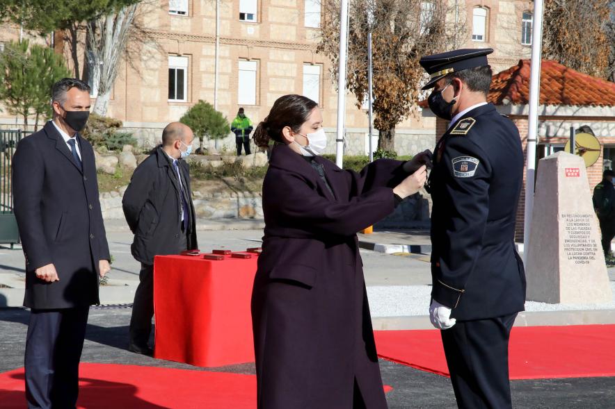 Presentación del ESICAM179 y Entrega de Medallas al Mérito Policial - Imagen de la Presidenta de la Comunidad de Madrid condecorando a un Policía, todos con mascarillas.