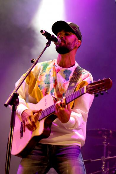 Cantante con guitarra bajo focos morados