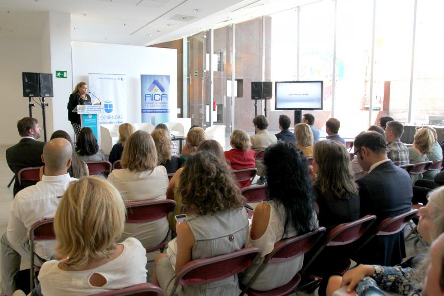 Ier Encuentro de Comercio Urbano de Alcobendas - Imagen panorámica del lugar donde se celebra el encuentro, personas asistentes y una oradora en el escenario.