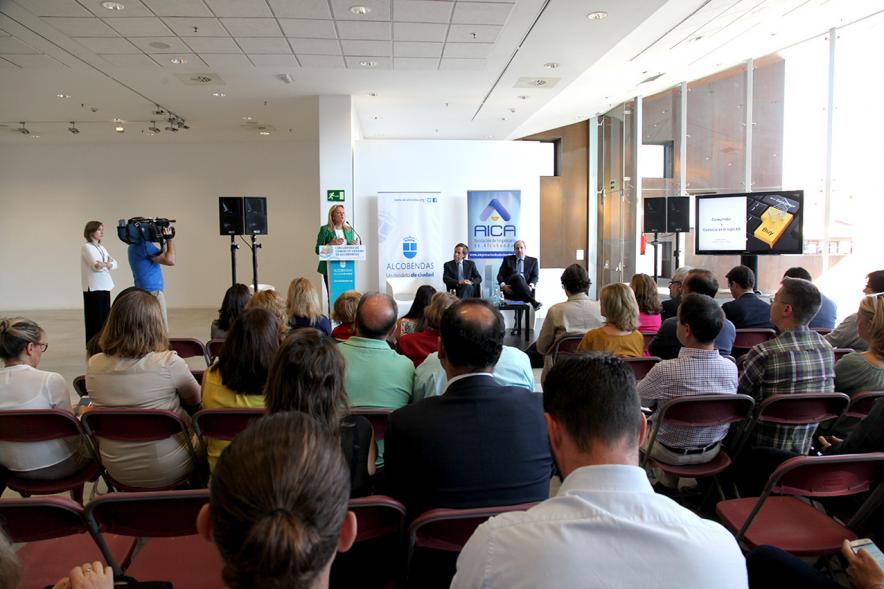 Ier Encuentro de Comercio Urbano de Alcobendas - Imagen panorámica del lugar donde se celebra el encuentro, personas asistentes y una oradora en el escenario.