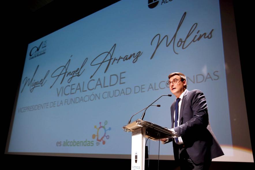Semana contra la Violencia de Género - Encuentro con Oihane Ruíz - Primer plano del vicealcalde Arranz, en el escenario, detrás  una diapositiva con su nombre.