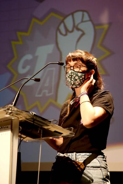 Semana contra la Violencia de Género - Encuentro con Oihane Ruíz - Primer plano de una joven dando un discurso junto a la proyección del cartel del encuentro.