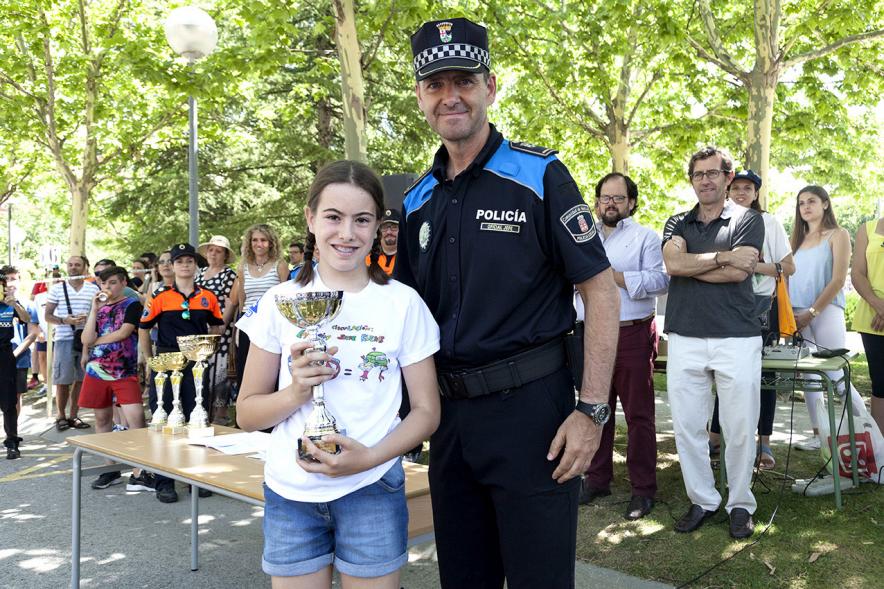 Entrega Premios XXIIº Concurso Escolar de Dibujo y Eslogan sobre Educaión y Seguridad Vial - Imagen de un niña premiado junto con una fuerza del orden asistente al acto.