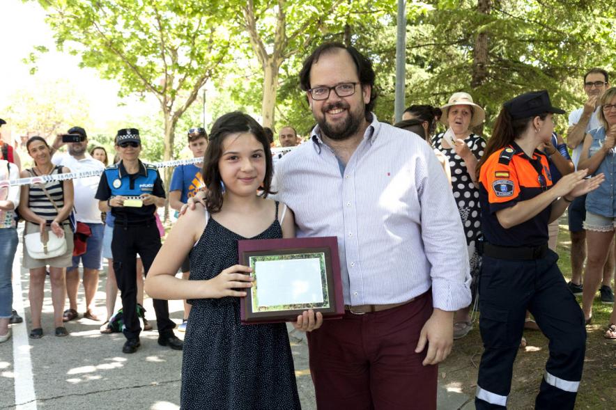Entrega Premios XXIIº Concurso Escolar de Dibujo y Eslogan sobre Educaión y Seguridad Vial - Imagen de una niña premiada junto con una autoridad asistente al acto.