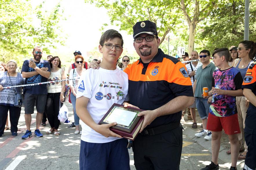 Entrega Premios XXIIº Concurso Escolar de Dibujo y Eslogan sobre Educaión y Seguridad Vial - Imagen de un niño premiado junto con una fuerza del orden asistente al acto.