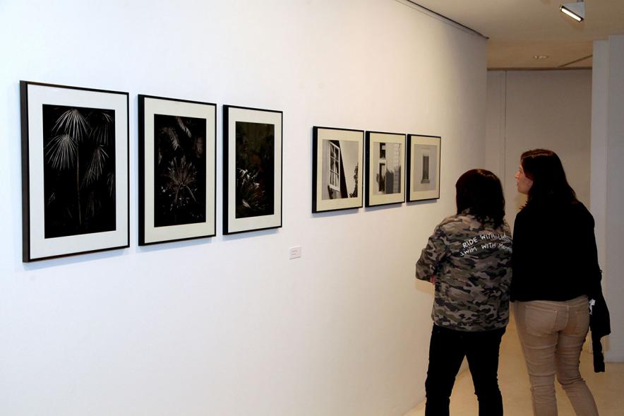 Entrega Premios VIIIº Concurso de Fotografía Ciudad de Alcobendas - Imagen de algunas obras expuestas y dos visitantes.