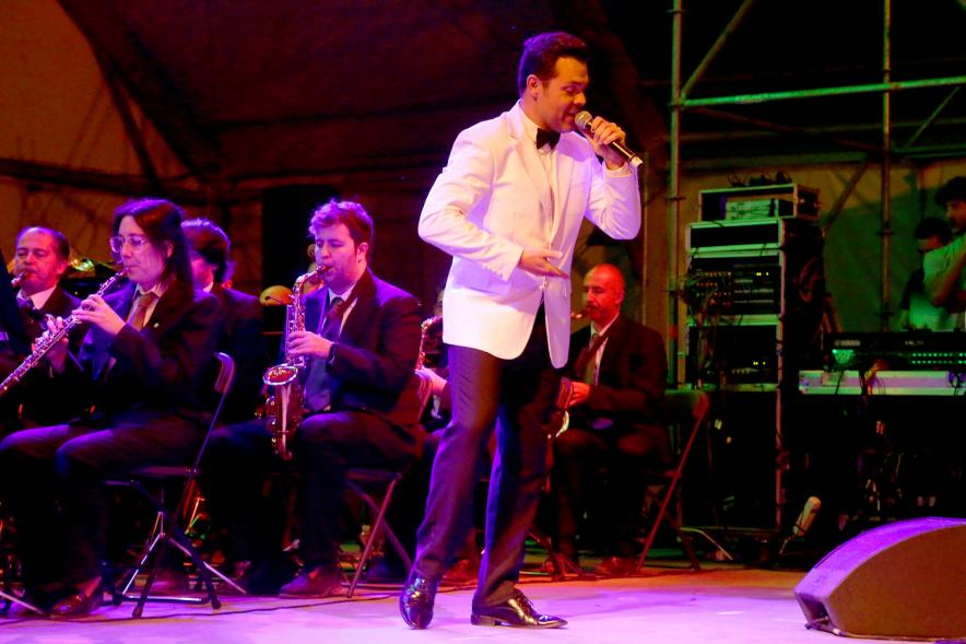 Cantante al micrófono bajo focos morados