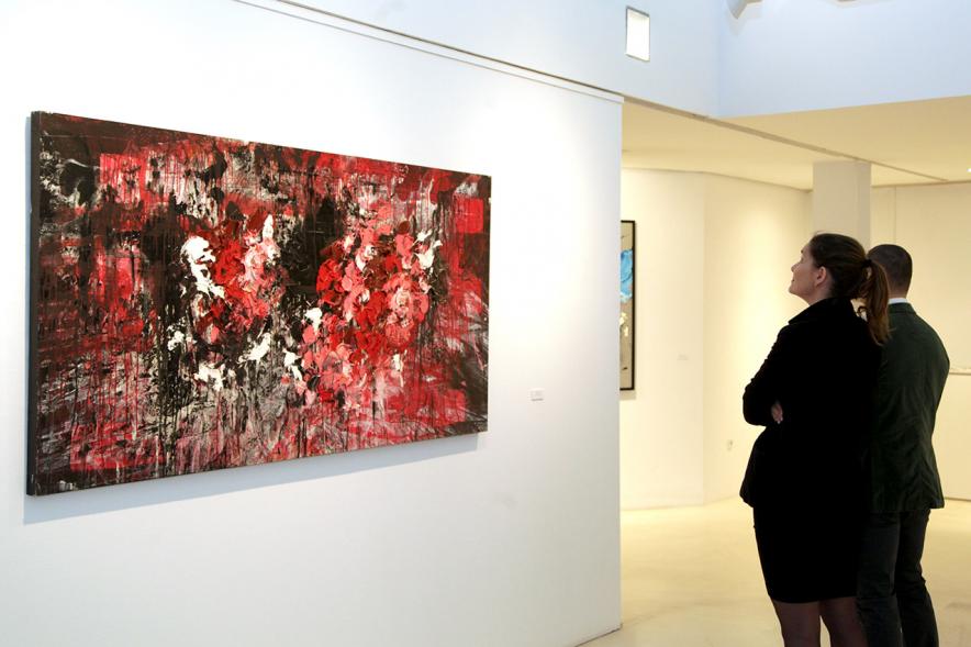 Inauguración de la Exposición de Manuel Martín Cabrera - Imagen de unas personas admirando uno de los cuadros expuestos en la exposición.