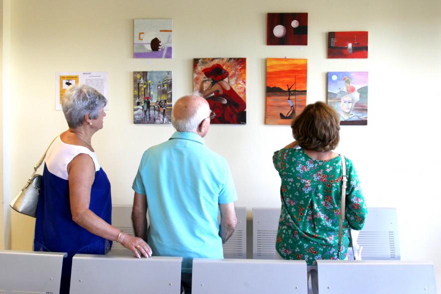 Inauguración Exposición Pintura en el Hospital Infanta Sofía - Imagen de personas admirando algunos de los cuadros expuestos.