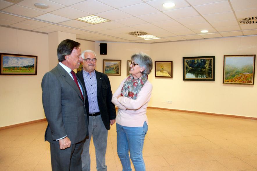 Semana Cultural Xuntanza de Galegos - Inauguración Exposición de Pintura de Esperanza Bouzas - Imagen del alcalde García de Vinuesa,Esperanza Bouzas y otra persona delante de los cuadros.
