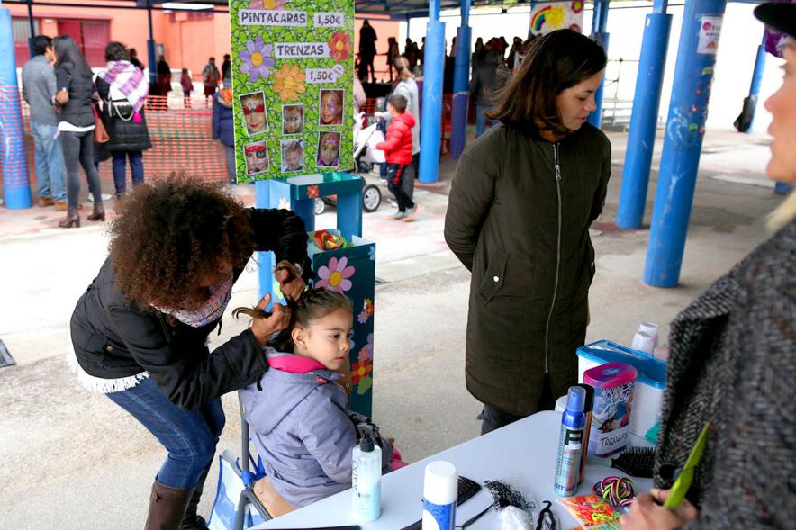 Niña haciéndose trenzas en el mercadillo