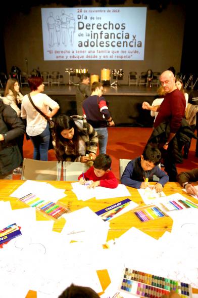 Fiesta Derechos de la Infancia - Primer plano de un grupo de niños jugando y el cartel del evento en la pantalla.