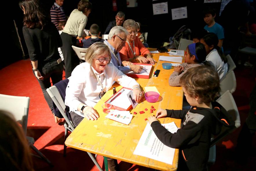 Fiesta Derechos de la Infancia -   Primer plano de un grupo de participantes mayores en una mesa  de actividades.