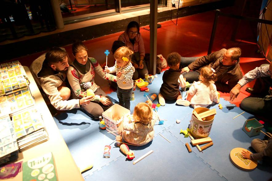 Fiesta Derechos de la Infancia -  Imagen semi en penumbra de un grupo niños con sus padres jugando.