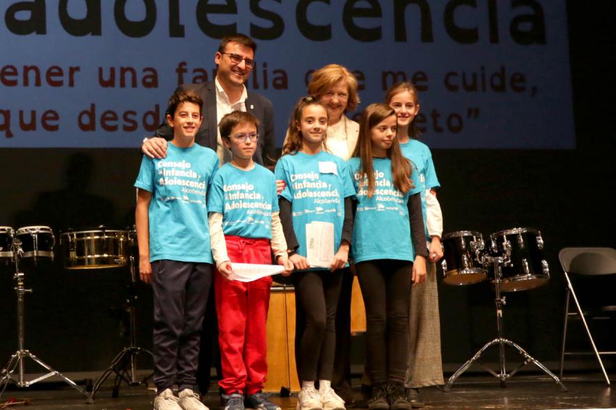 Fiesta Derechos de la Infancia - Posado del vice alcalde Miguel Ángel Arranz y Ofelia Culebradas  con unos niños en el escenario.