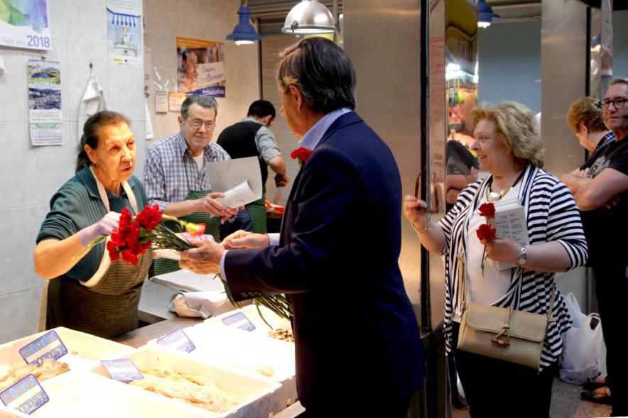 Delegación municipal en el mercado entregando el programa de fiestas en una pescadería