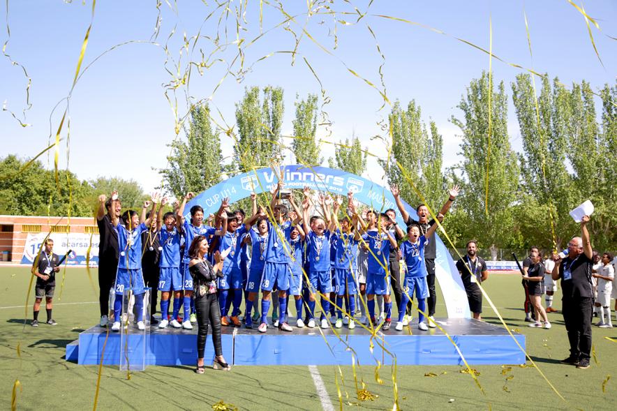 Torneo Internacional de Fútbol Madrid Football Cup U14 - Imagen del equipo gandador en el pódium celebrando la victoria, después de haber recibido el trofeo de ganador.