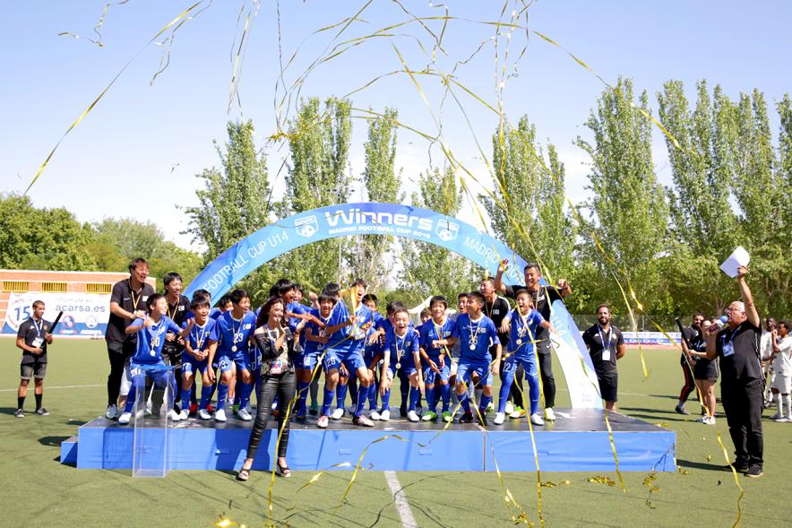 Torneo Internacional de Fútbol Madrid Football Cup U14 - Imagen del equipo gandador en el pódium celebrando la victoria, después de haber recibido el trofeo de ganador.